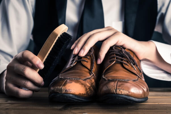 a man brushes his classic leather shoes