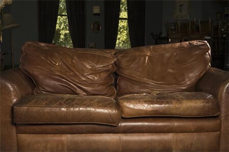 a well-worn leather couch showing major signs of stretching and sagging